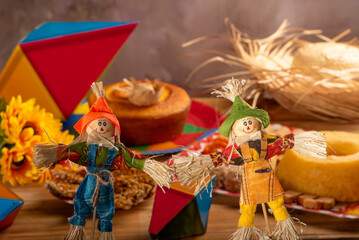 Festa Junina, straw dolls in front and in the blurred background a table full of sweets from the Brazilian Festa Junina, selective focus.