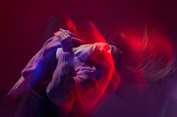 A young woman dances contemporary dances in blue and red light. Long exposure photo. 