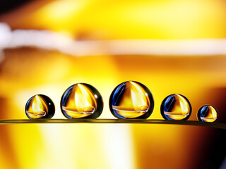 Closeup shot of five water droplet formed on a grass blade with burning match reflection inside the...