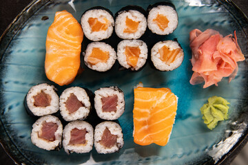 Top view of traditional japanese cuisine . Sushi rolls set with salmon , tuna fish and vegetable served on black stone table . Asian food on black stone slate with chopsticks .