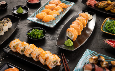 Top view of traditional japanese cuisine . Sushi rolls set with salmon , tuna fish and vegetable served on black stone table . Asian food on black stone slate with chopsticks .