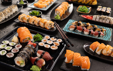 Top view of traditional japanese cuisine . Sushi rolls set with salmon , tuna fish and vegetable served on black stone table . Asian food on black stone slate with chopsticks .
