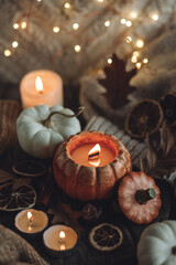 Atmospheric candle - shape of pumpkins, autumn decor on grey fall rainy day. Autumn cozy home atmosphere and inspiration, hygge concept. Aromatherapy, warming, relaxation. Wooden background