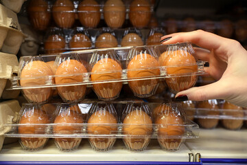 A person is reaching for a carton of eggs