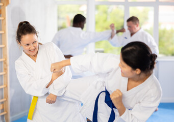 Sportive middle-aged woman trainee of karate courses applying attack methods on her partner