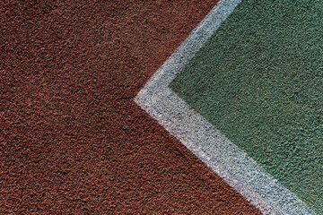 overhead view of the white lines marking a tennis court, revealing the textured surface of the court