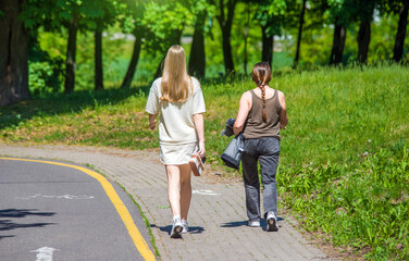 Obraz premium Two girlfriends walk along a path in the Park 