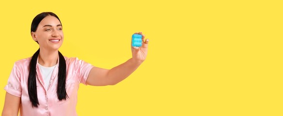 Happy woman with dental floss on yellow background with space for text