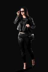Beautiful stylish young woman in leather jacket on black background