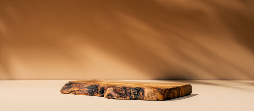 Table with rustic wood podium for food, cosmetic products, perfumes against beige background. Front view.
