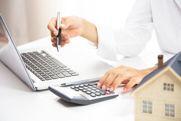 Real estate agent working with laptop at table in office.hand using laptop and calculator