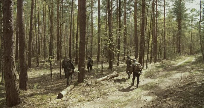 Reenactors Dressed As German Infantry Soldiers Marching By Forest Autumn Season. Group Of Soldiers With Carabines Mauser 98k, Panzerschreck Combing Forest. Wermacht Military Uniform. Reenactment Game