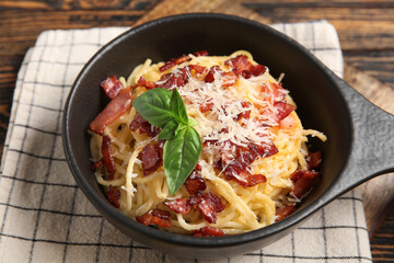 Frying pan with tasty pasta carbonara on wooden background