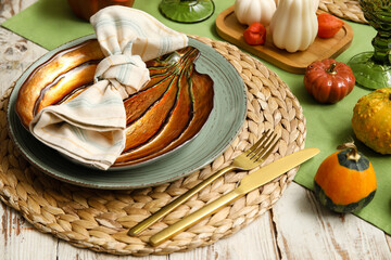 Autumn table serving with golden cutlery and plate in shape of pumpkin on white wooden table, closeup