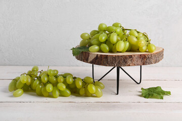 Clusters of green grapes on stand against wooden background