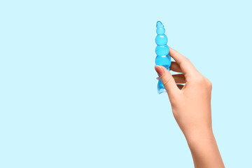 Female hand with anal plug on blue background