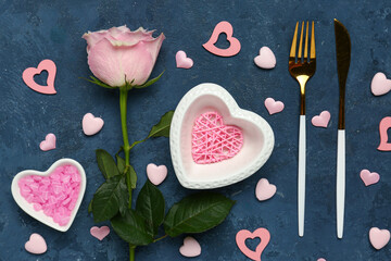 Beautiful table setting for Valentine's Day with pink hearts and rose on blue grunge background