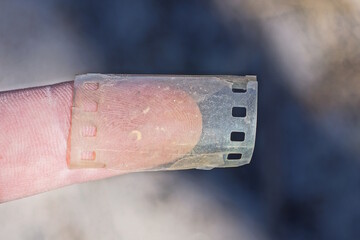 a piece of old grey photographic film is wound around a finger on a hand