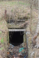old bunker with empty entrance without door in gray earth on the street