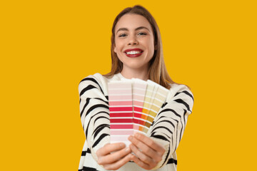 Young woman with color palettes on yellow background