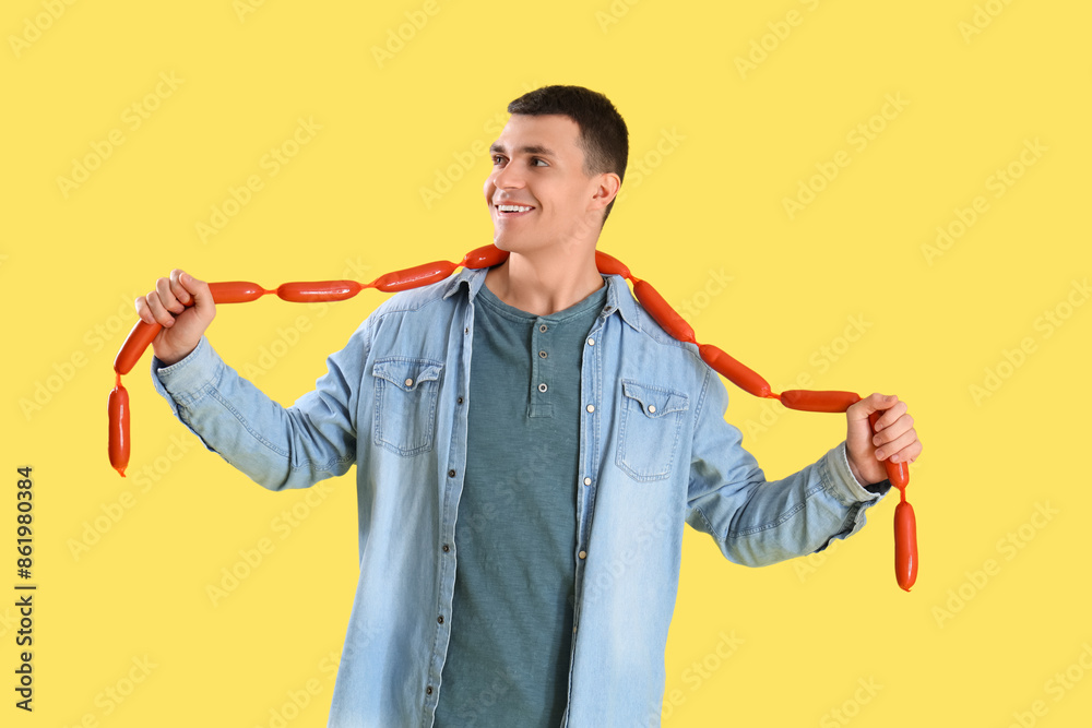 Canvas Prints Young man with tasty sausages on yellow background