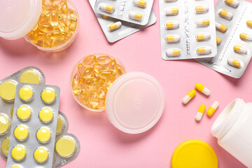 Different pills and bottle of medicines on pink background
