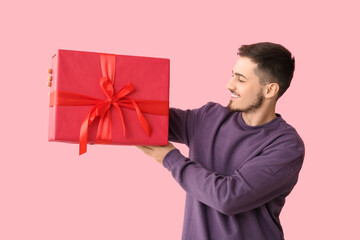 Handsome man with gift box on pink background