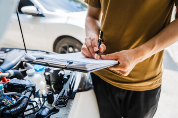 Man fills out a car insurance form after a car accident. Comprehensive motor insurance covers car damage. He files a claim report, speaking with an adjuster to understand his coverage and deductible.
