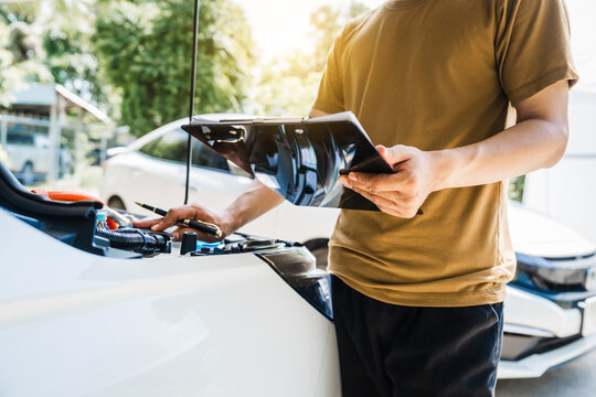 Man fills out a car insurance form after a car accident. Comprehensive motor insurance covers car damage. He files a claim report, speaking with an adjuster to understand his coverage and deductible.