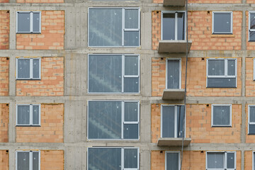 new building the real estate market. New construction building. red clay ceramic thermo brick multi-story building before insulation and cladding. New windows installed,