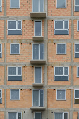 new building the real estate market. New construction building. red clay ceramic thermo brick multi-story building before insulation and cladding. New windows installed,