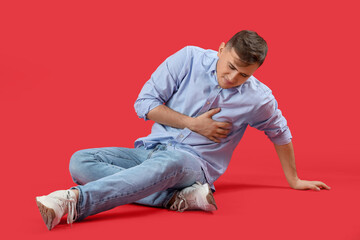 Young man suffering from chest pain on red background