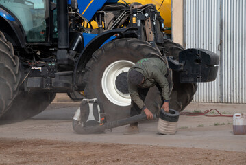 Joven limpiando filtro de tractor con sopladora portátil en zona rural