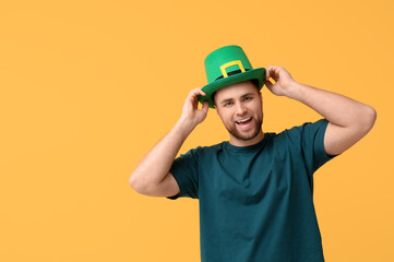 Happy young man in leprechaun's hat on yellow background. St. Patrick's Day celebration