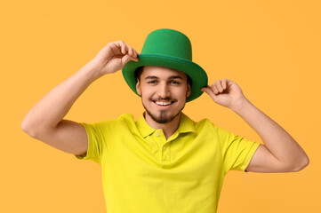 Happy young man in leprechaun's hat on yellow background. St. Patrick's Day celebration