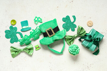 Leprechaun hat with cupcake, gift box and decor for St. Patrick's Day on white grunge background