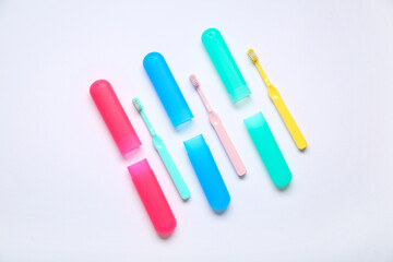 Colorful toothbrushes in cases on white background