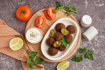 Plate with delicious falafel balls, sauce and tomato on grunge background