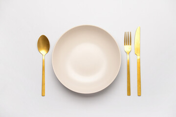 Bowl with golden cutlery on white background