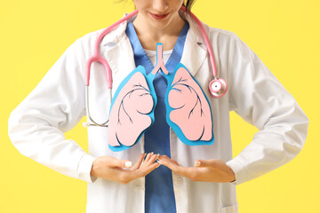 Female doctor with paper lungs on yellow background