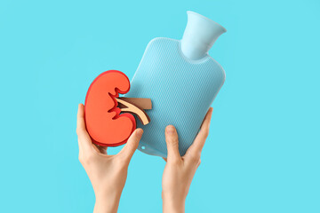 Woman with paper kidney and hot water bottle on blue background