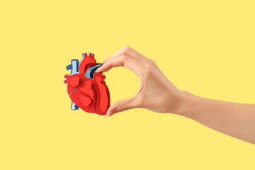 Woman with paper heart on yellow background