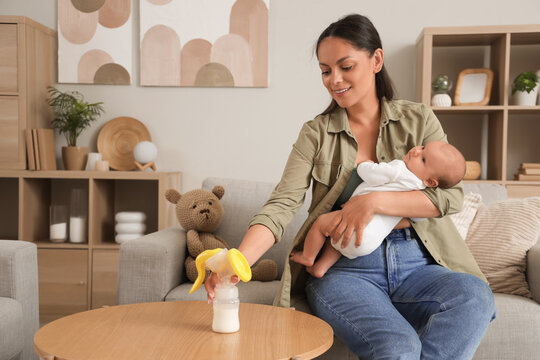 Mother with her baby taking breast pump from table at home