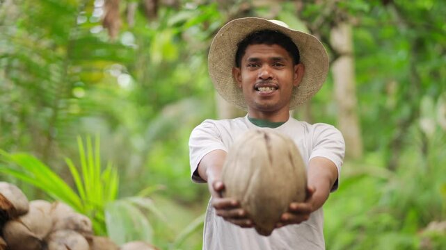 Authentic portrait of smiling young indonesian coconut farmer with straw hat on farm, youth in agriculture in developing country