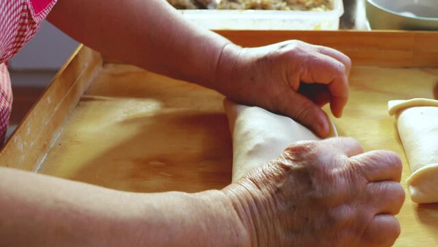 Unrecognizable elderly latin woman making chilean meat baked empanadas in her kitchen. Traditional pastry.