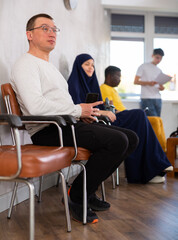 Man sitting in lobby of job center or employment office, waiting for interview or conversation with...