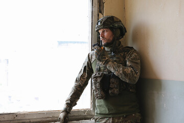 Military mission. Soldier in uniform with radio transmitter inside abandoned building, space for...