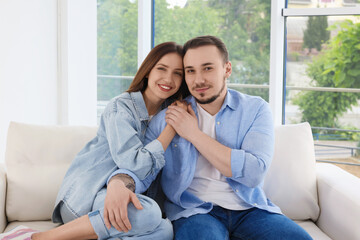 Obraz premium Happy couple holding hands on sofa at home