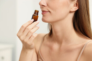 Aromatherapy. Woman with bottle of essential oil on light background, closeup