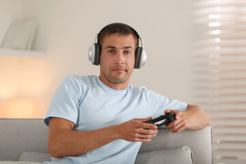 Man in headphones playing video games with joystick at home